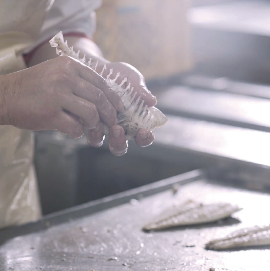 Hands removing bones from a fish by hand at the factory