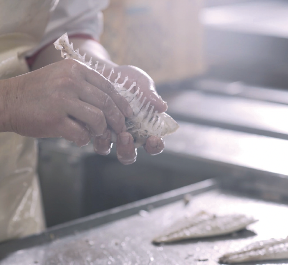 A skilled cannery worker preparing fish carefully by hand