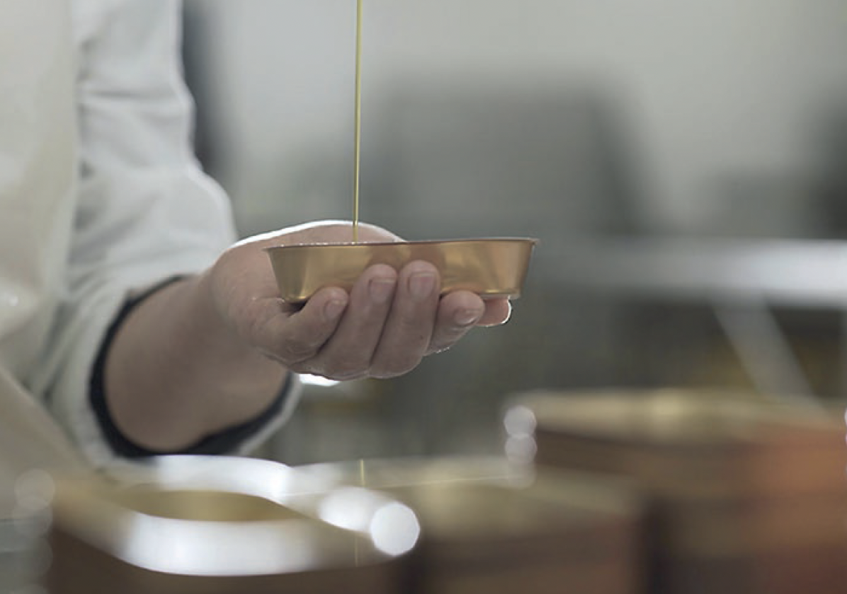 Olive oil being poured by hand into a tin